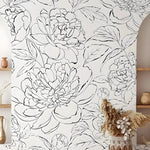 Black and White Line Art Peony mural in boho room with large ink peony blooms, pampas grass in wicker vase, and wood shelves