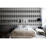 Black and white geometric leaves wallpaper as bedroom headboard wall with framed artwork and white bedding