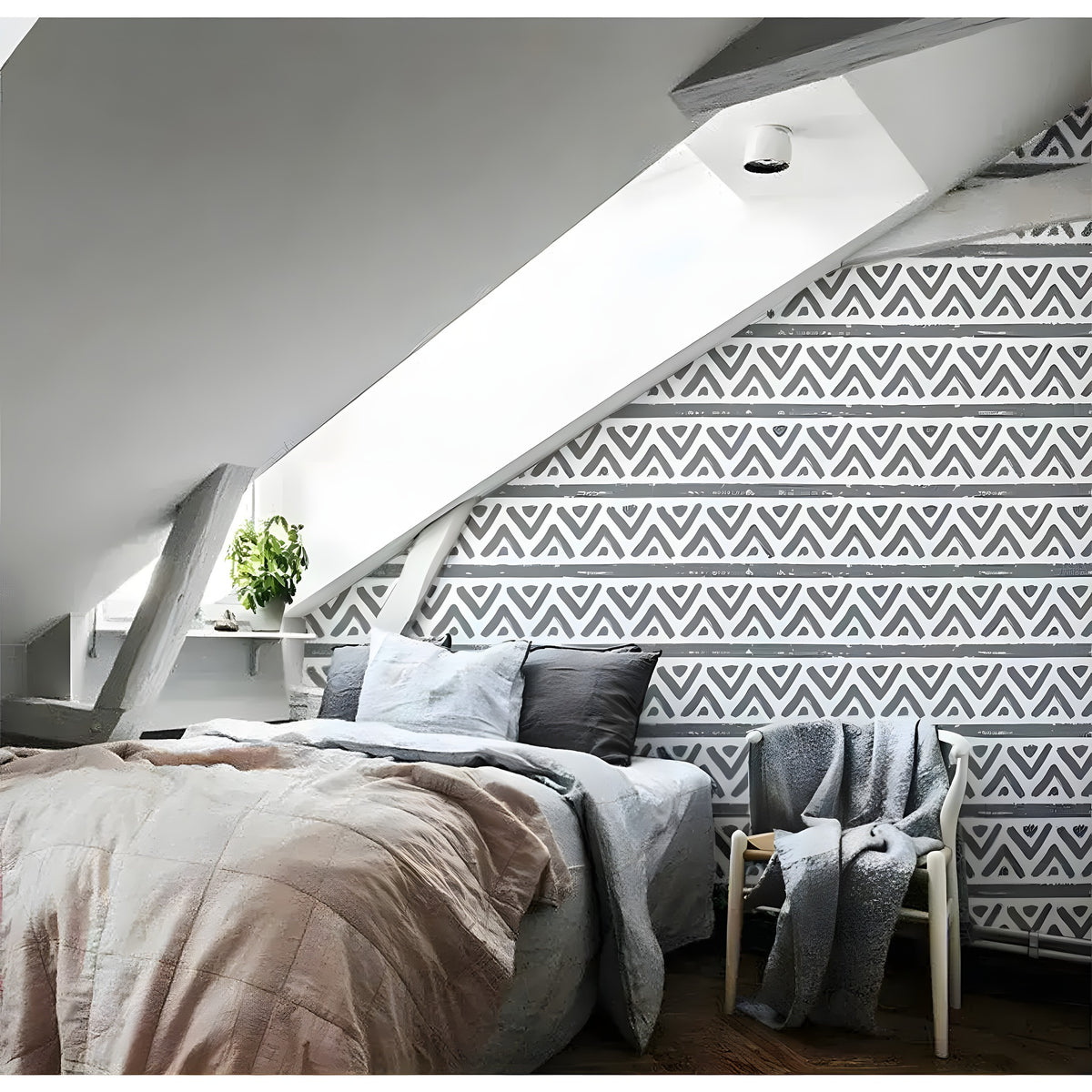 Bold geometric triangle and line wallpaper on accent wall in attic bedroom with sloped ceiling