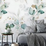 Eucalyptus watercolor botanical wallpaper behind a grey sofa in a cozy living room