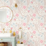 Nursery floral wallpaper in a child's bathroom with pink and blue flowers, gold fixtures and round mirror