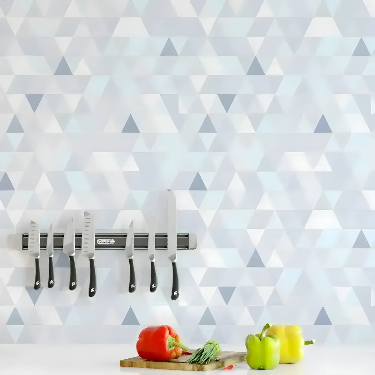 Blue and white geometric triangle wallpaper behind a kitchen knife magnetic rack with fresh peppers