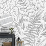 Gray fern botanical wall mural in a bathroom with dark vanity, round mirror, and wooden stool