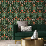 Alaia vintage dark botanical wallpaper installed in a living room with emerald sofa, pillows, and gold round coffee table