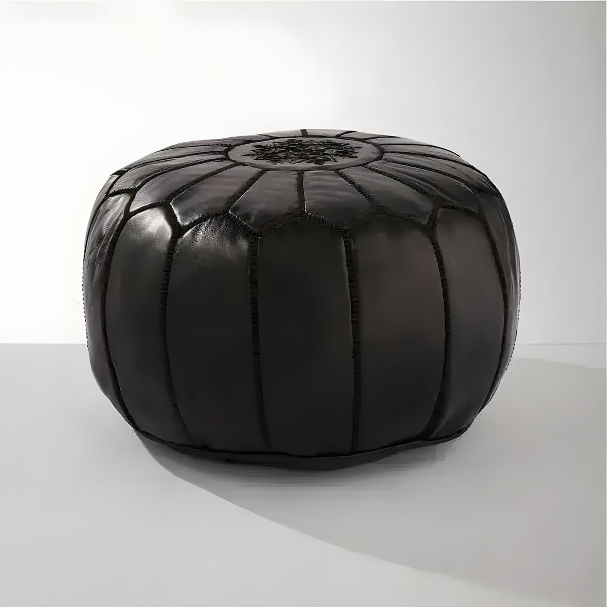 Black genuine leather round floral pouf ottoman — front view with hand-stitched petal segments, white background