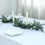 Faux olive branch garland on white dining table with ivory taper candles and hexagonal gold-rimmed dish