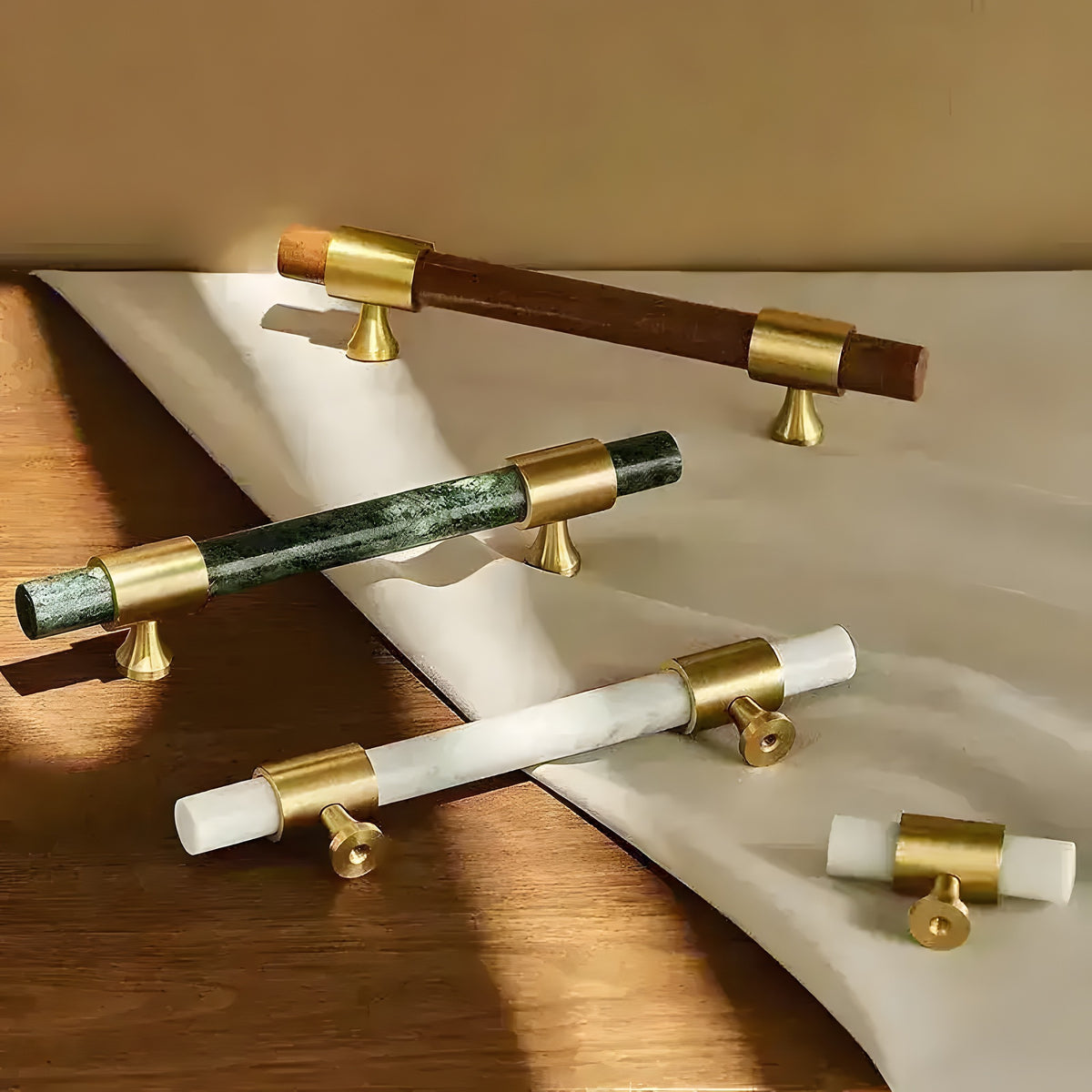 Three Meg cabinet pulls (brown, green, white marble bars with brass caps) plus two knob variants displayed on wood surface