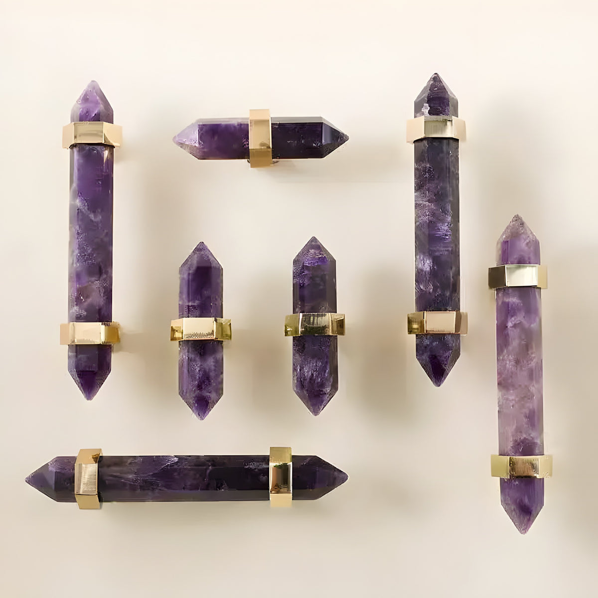 Seven purple amethyst bar drawer pulls with brass brackets arranged on beige flat lay