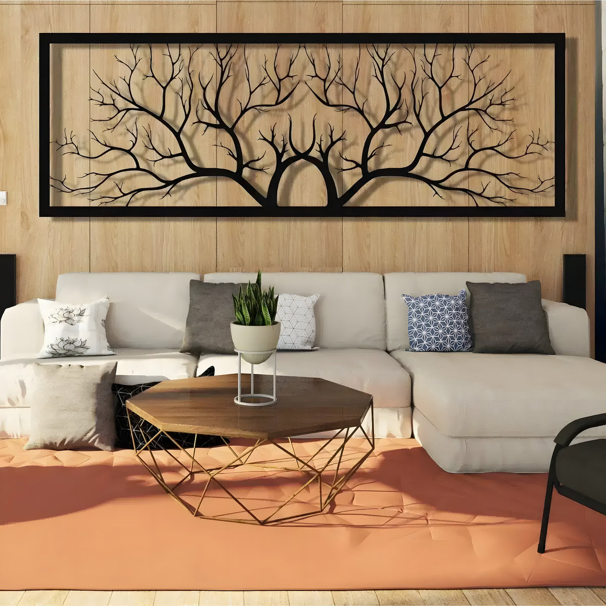 Black horizontal tree branch metal wall hanging in black frame above cream sofa on wood-paneled wall