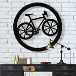 Black bicycle in circle metal wall art on white brick wall above dark industrial drawer unit and brass lamp
