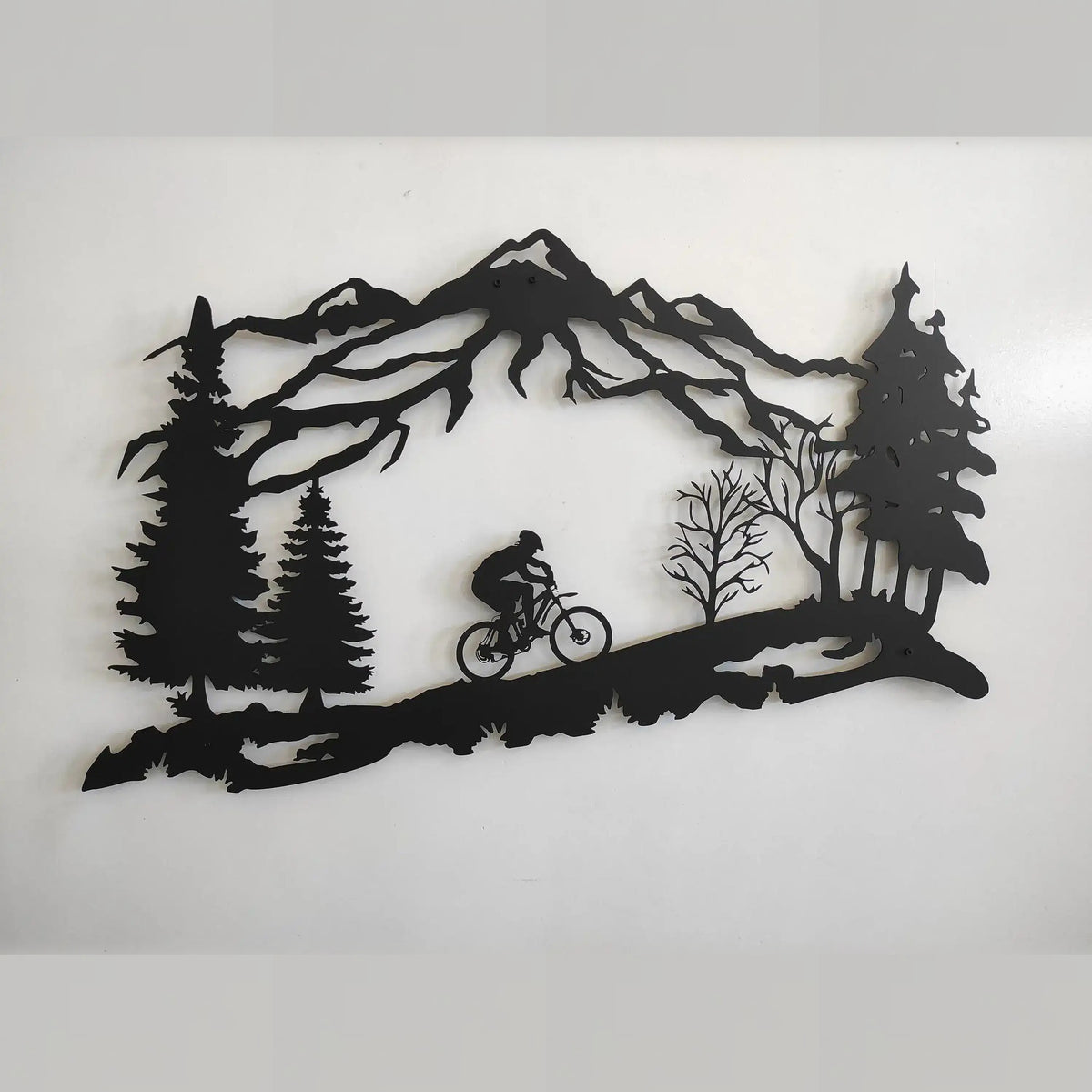Black Mountain Biker metal wall decor showing cyclist in mountain landscape with pine trees, flat view