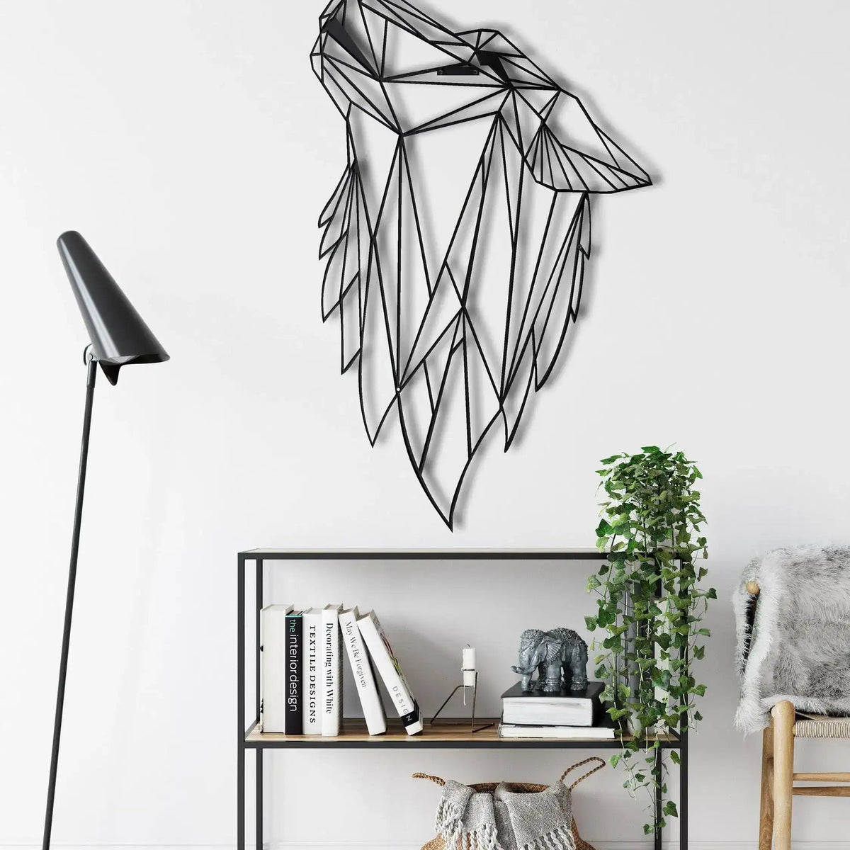 Black geometric wolf head metal wall decor howling, angular facets, on white wall with shelf and lamp