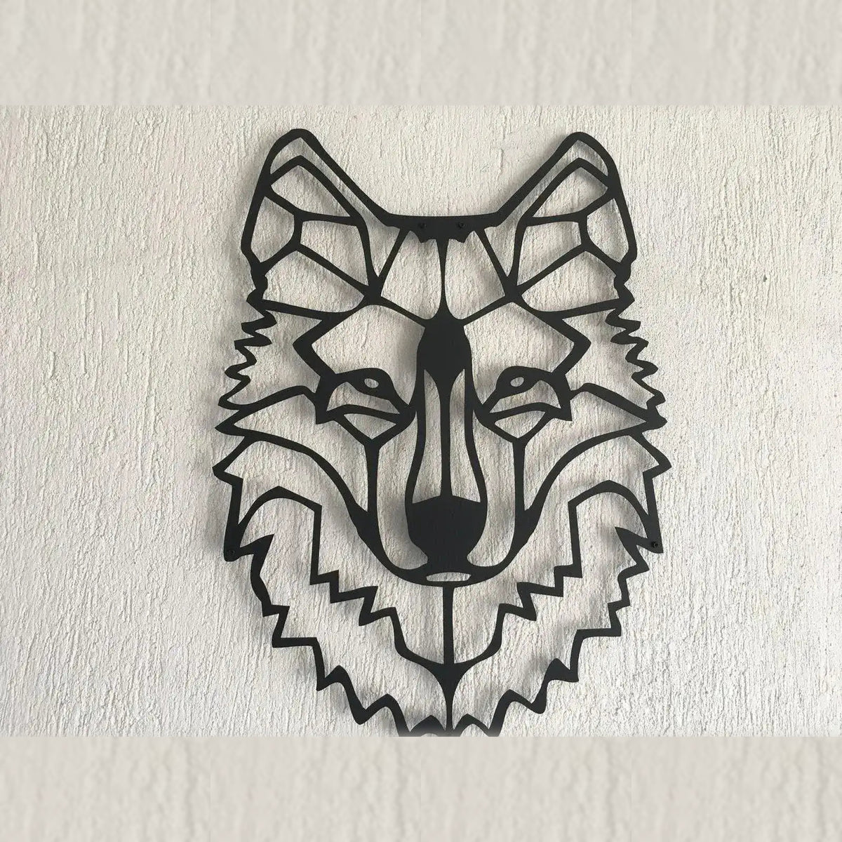 Black geometric wolf head metal wall hanging, angular front view on white textured wall