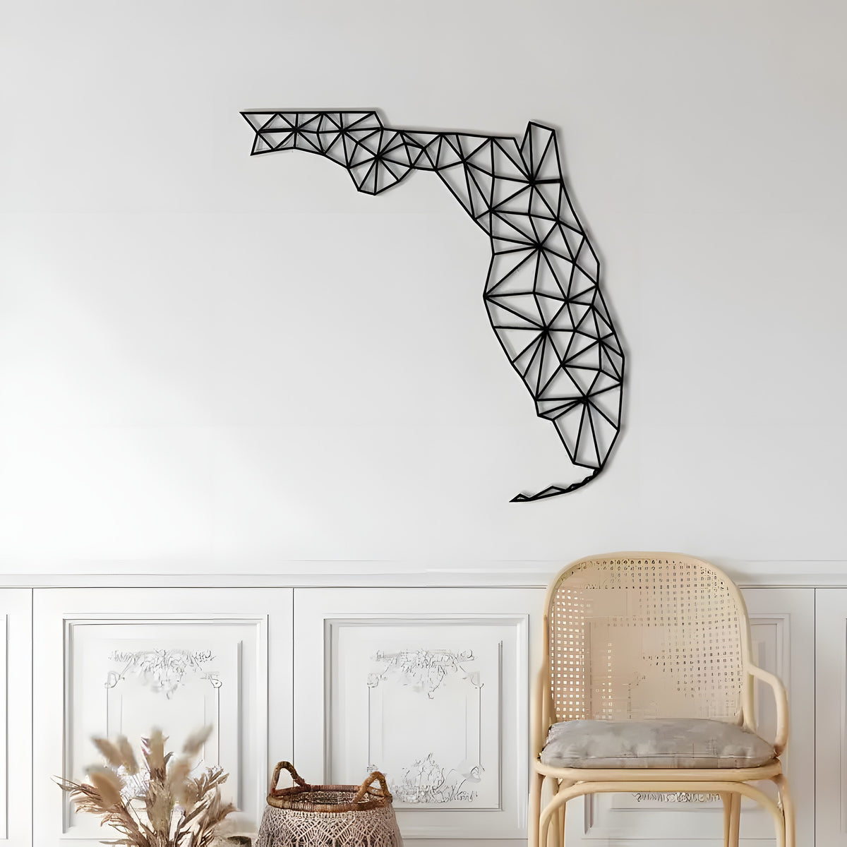 Black geometric Florida map metal wall decor on white panelled wall with rattan chair below