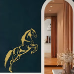 Gold jumping horse metal wall art on dark navy wall beside white arch, dried floral vase below