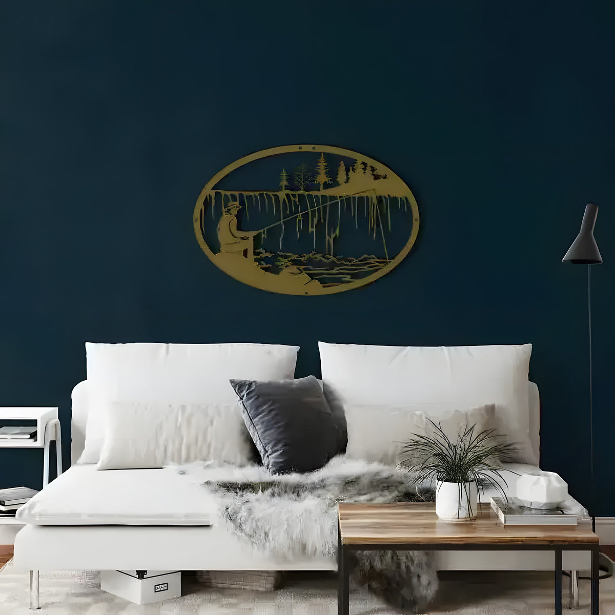 Gold oval fisherman metal wall art with figure casting rod on lake, pine trees above white sofa on navy