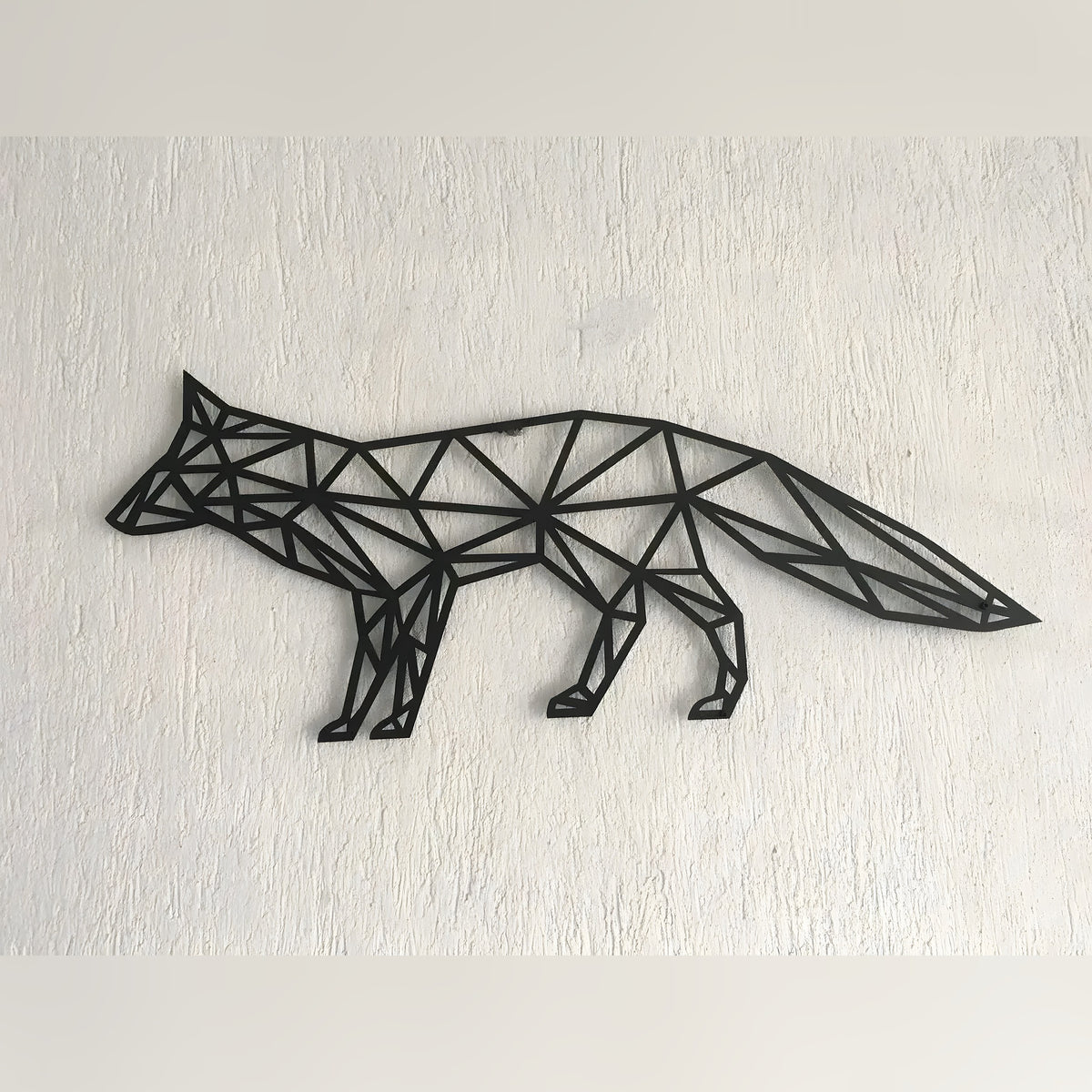 Black geometric fox metal wall art in walking profile, triangular polygon cutouts on white textured wall