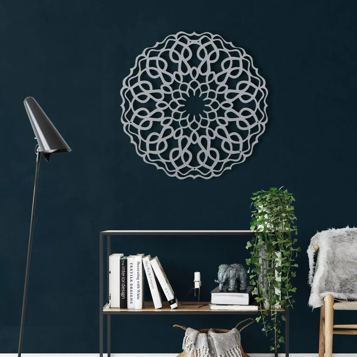 Silver round mandala metal wall art with interlocking loop pattern on dark teal wall