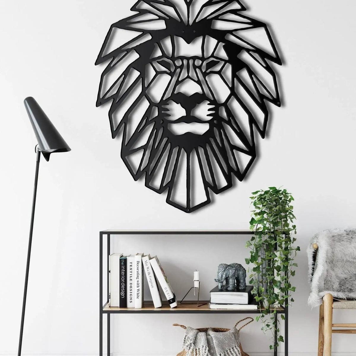 Black geometric lion head wall decor in room setting above bookshelf with floor lamp and ivy plant