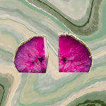 Pair of pink plated agate bookends, fuchsia geode slices with silver plated edges, top view on green marble background