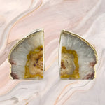 Pair of natural clear agate bookends with gold-plated edges on pink marble background