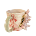 Pink quartz marbled ceramic coffee mug, white-pink swirl pattern with green handle and protruding pink crystal cluster
