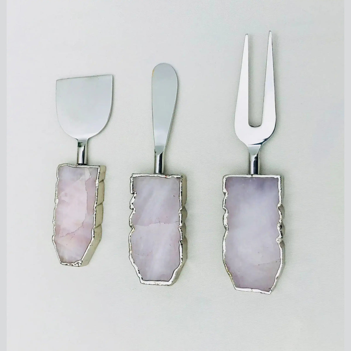 Three agate-handled rose quartz cheese knives with blue agate and gold foil edges, fork, spreader and wide blade