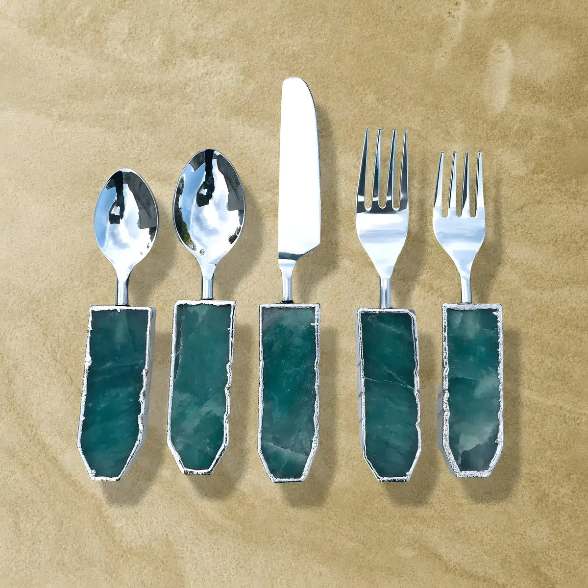 Green agate cutlery set of 5, two spoons, knife and two forks with dark teal agate handles and silver trim on tan background