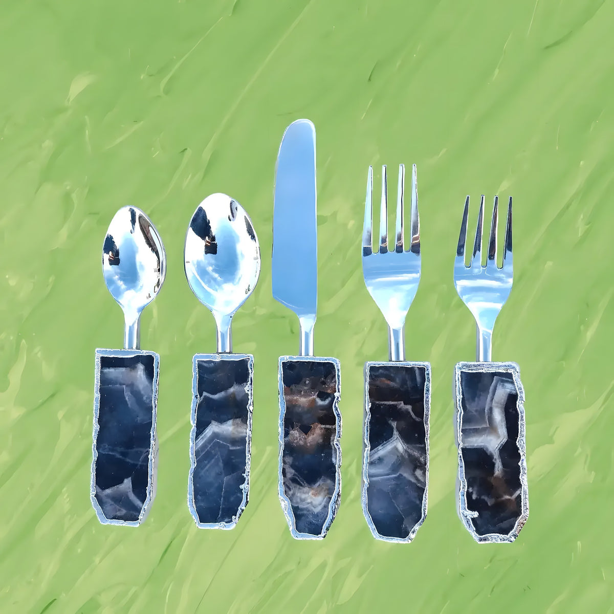 Five-piece amethyst cutlery set on green background, silver spoons, knife and forks with dark banded agate handles, overhead