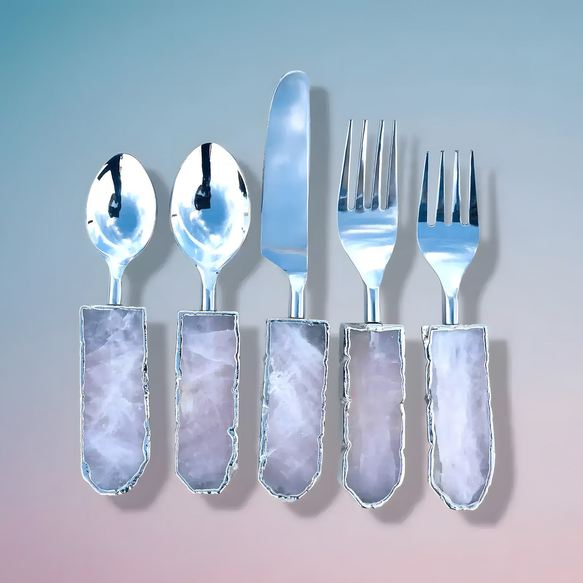 Five rose quartz agate cutlery pieces fanned on blue-pink gradient, pink-lavender agate handles, silver jagged edges