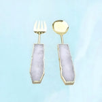Rose quartz salad server set, gold fork and spoon with pale lavender-pink quartz handles in gold trim, front on aqua background