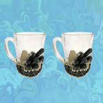 Two clear glass handled mugs with black tourmaline crystal cluster base and gold accent on blue marble-patterned background
