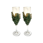 Two dark green quartz champagne flutes with crushed green crystal chip bases and jagged gold crown collar on clear glass flutes