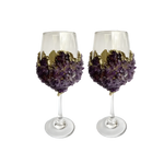 Two purple quartz wine glasses side by side, amethyst crystal chip clusters on each bowl, gold accent band, clear stems.