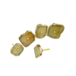 Five mustard agate cabinet knobs scattered showing warm olive-yellow stone faces with gold rims, one showing mounting screw
