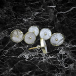 Six round clear quartz cabinet knobs with gold bezels on black marble surface, one showing screw post hardware