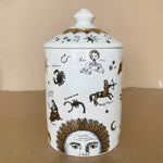 White ceramic gold-gilded zodiac sign candle jar with domed lid, decorated with etched Sagittario, Cancro, Vergine and sun face illustrations