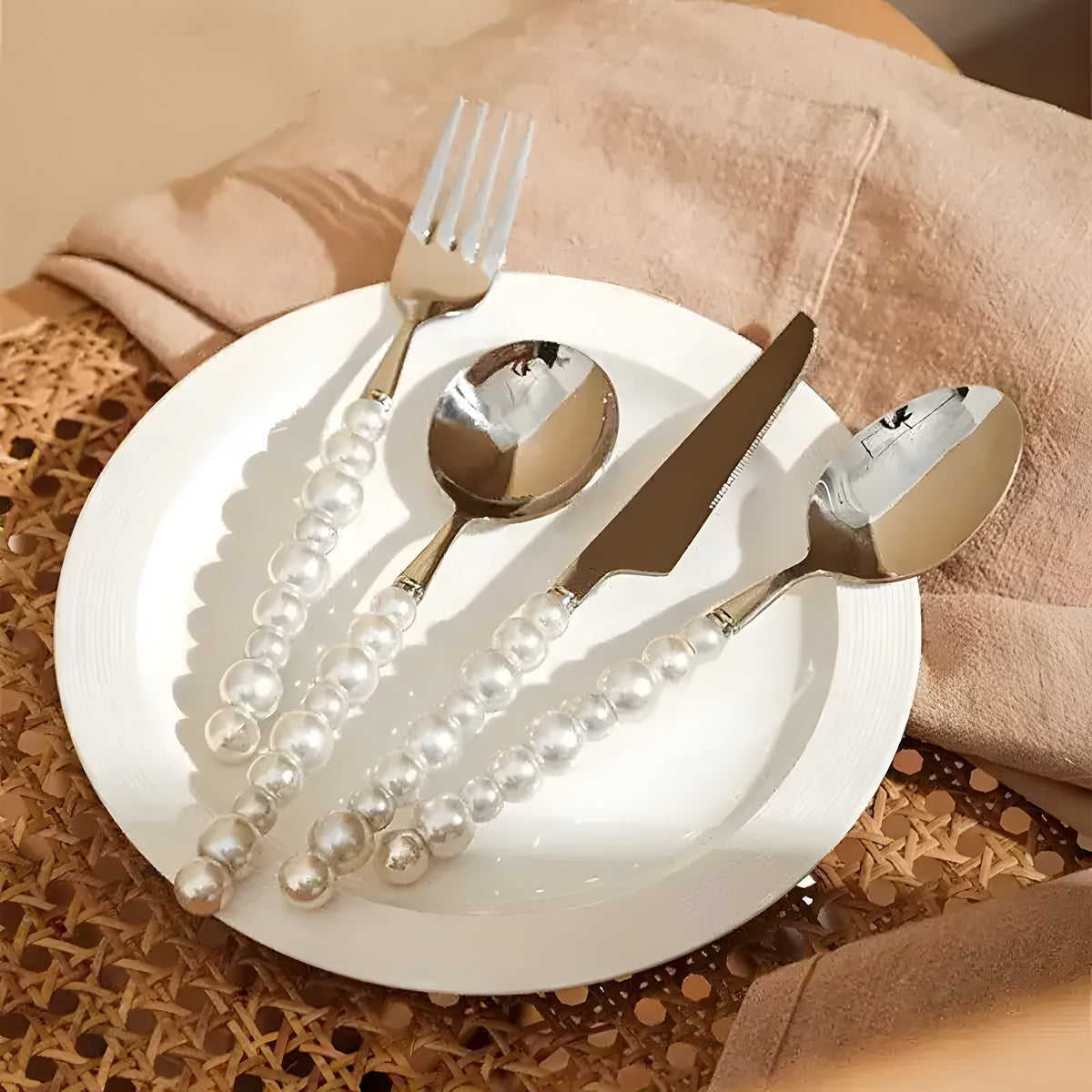 Pearl-handle stainless flatware set — fork, knife, 2 spoons on white plate, woven placemat