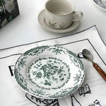 Rose dessert plate with dark green floral print, ornate scalloped border, styled at table with teacup