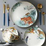 White bone china plate with painted lioness and cub in jungle setting, gold-edged rim, styled with gold cutlery