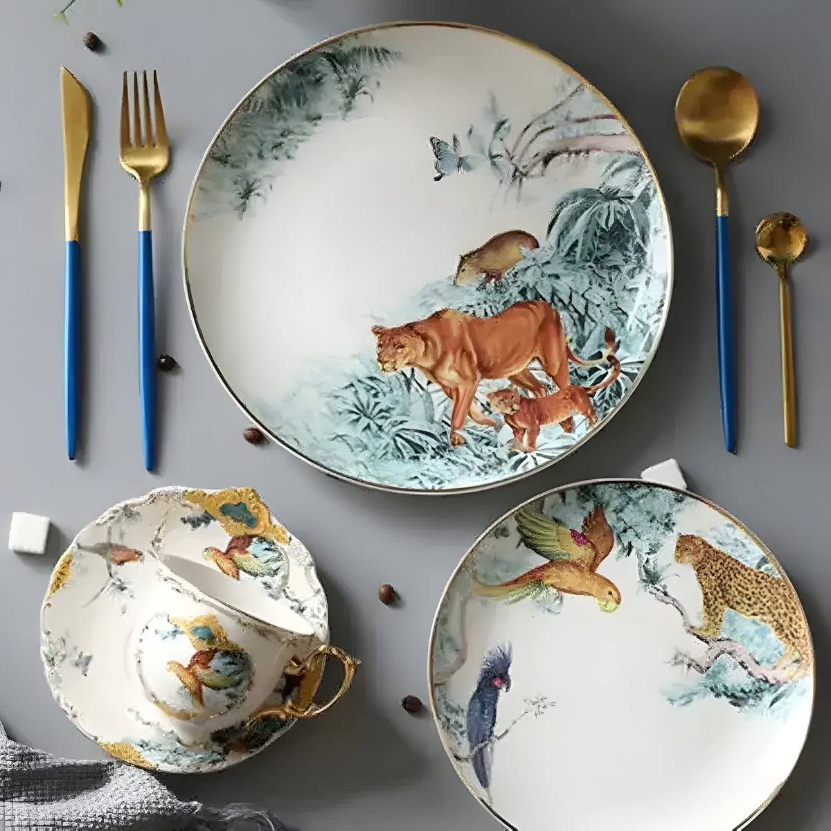 White bone china plate with painted lioness and cub in jungle setting, gold-edged rim, styled with gold cutlery