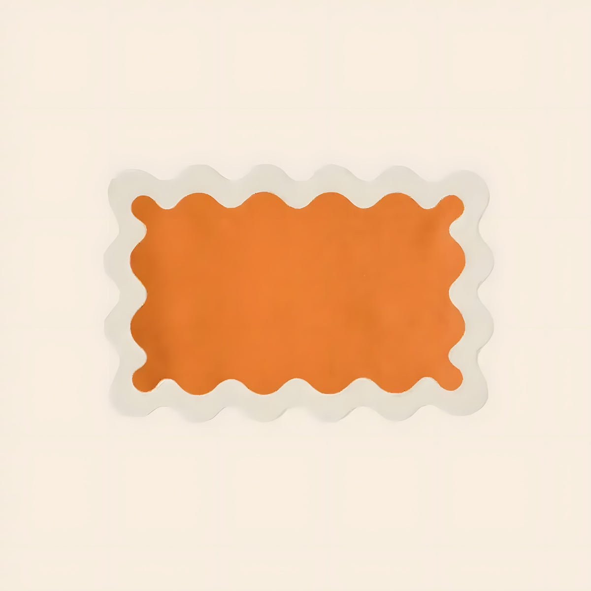 Single orange linen scallop placemat on cream background, rectangular with wavy white scallop border, flat lay
