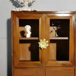 Gold brass lotus floral cabinet knob on double-door wooden display cabinet with glass panels