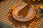 Hazelnut Haven Placemats brown scalloped with white dot border, styled with gold-rimmed plates and gold cutlery on check cloth