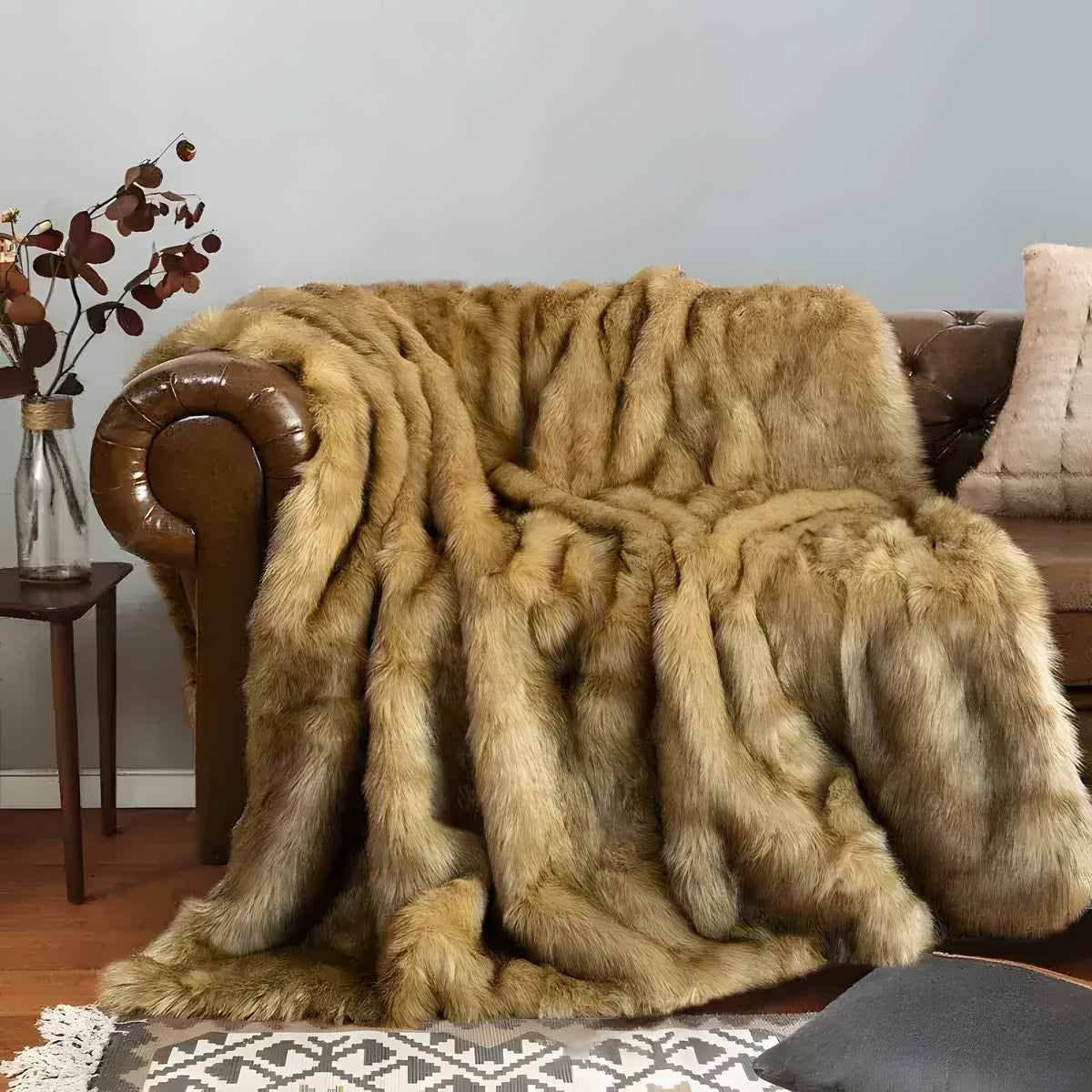 Luxury Faux Fur Blanket in warm golden-brown draped over leather Chesterfield sofa, long striped fur pile, cozy in-home setting