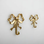 French Retro Bow Shape Brass Wall Hook in gold, two sizes shown side by side on white wall, ornate ribbon bow with hook