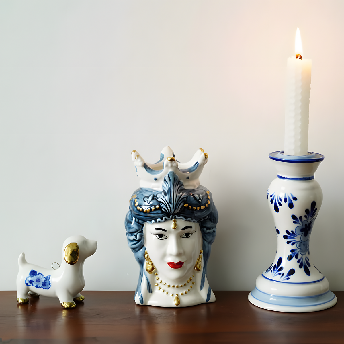 Decorative ceramic pieces including a face-shaped vase, small dog figurine, and candle holder on a wooden surface.