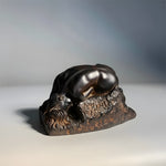Bronze sculpture of a lion on a stone base against a gradient background