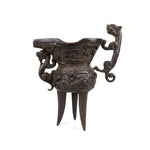 Hand holding a intricately carved wooden object with detailed carvings on a wooden surface.