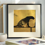 Framed artwork of a leopard on a gold background in a room setting.